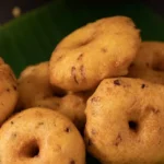 Golden-brown fried Ulundu Wade served traditionally on a vibrant green banana leaf backdrop